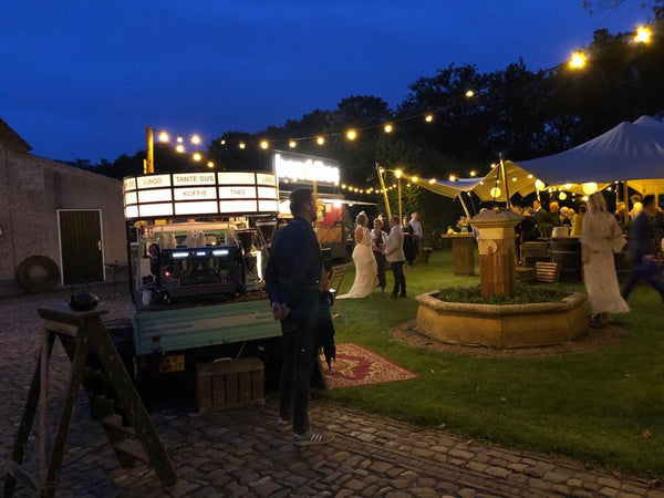 Mobiele koffiebar op een bruiloft met mooie sfeerverlichting.